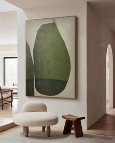 a painting hangs on the wall above a chair and footstool in a living room