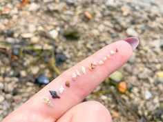 a person's finger with small pieces of gold on it and some rocks in the background