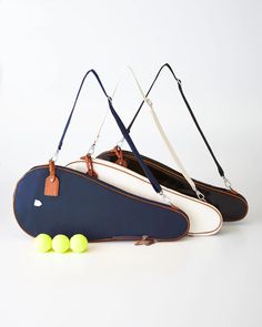 three tennis rackets and four balls on a white surface with strap around the handles