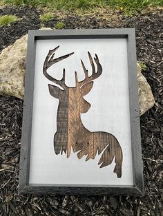 a wood cut out of a deer's head is displayed in front of a rock