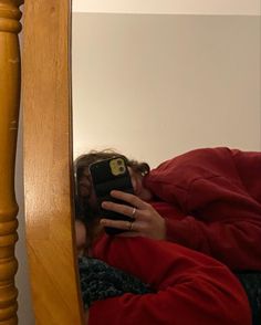 a woman taking a selfie in the mirror with her cell phone while laying down