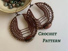 a pair of earrings sitting on top of a table next to a bowl with beads