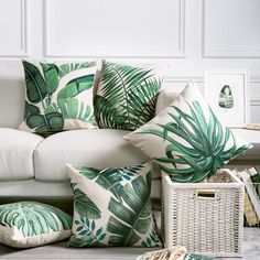 a living room filled with white furniture and green pillows on top of each other's cushions