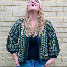 a woman is standing in front of a brick wall with her hands on her hips