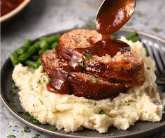 a plate with mashed potatoes, green beans and meat being drizzled on top