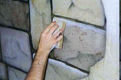 a man is painting a brick wall with white and gray paint on it's surface