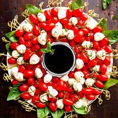 a platter with cherry tomatoes and mozzarella skewers on it, next to a cup of coffee