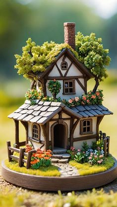 a miniature house with flowers and trees on the roof is shown in front of a grassy field