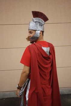 a man dressed up as a roman soldier in front of a garage door wearing a helmet and red cape