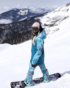 a person on a snowboard in the snow with mountains in the backgroud