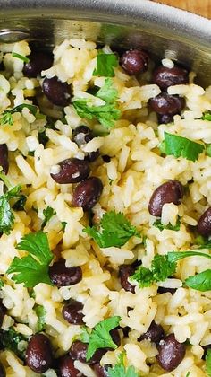 rice with beans and cilantro in a silver bowl on a wooden table top