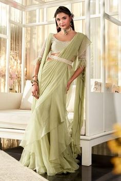 Mint green pre-draped saree with ruffle hem. Comes with scoop neckline embroidered blouse with feather hem sleeves and tassel embellished belt.
Component: 3
Pattern: Embroidered
Type Of Work: Floral Motifs
Neckline: Scoop
Sleeve Type: Half
Fabric: Blouse and Belt: Net; Saree: Chiffon, Organza
Color: Green
Other Details: 
Pre-draped saree
Ruffle hem saree
Tassel embellished blouse
Back cut-out blouse
Tassel hem belt
Feather hem sleeves
Note: Only selling the product mentioned in the description f Saree Chiffon, Yellow Drapes, Ridhi Mehra, Draped Saree, Saree Tassels, Net Blouses, Ruffle Saree, Embroidered Crop Tops, Embroidered Belt