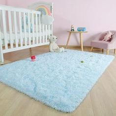 a baby's room with pink walls, white crib and blue rugs