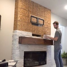 a man standing in front of a fireplace with a tv on it's mantle