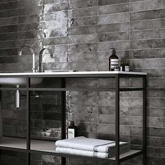 a black and white photo of a bathroom sink with towels on the shelf next to it