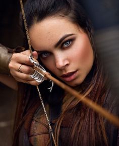 a beautiful young woman holding an arrow in her hand