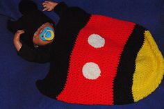 a crocheted mickey mouse hat laying on top of a blue blanket with white polka dots