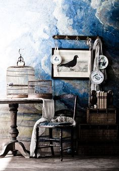 a birdcage sitting on top of a table next to a chair and clock