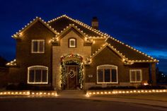 a house with christmas lights on the front and side of it at night, lit up