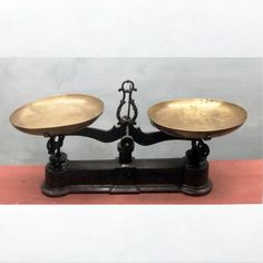 two metal bowls sitting on top of each other in front of a white wall and red floor