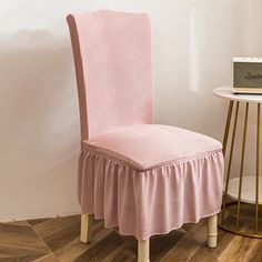 a pink chair sitting next to a white table with a clock on top of it