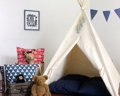 a teepee tent sitting on top of a wooden floor next to pillows and blankets