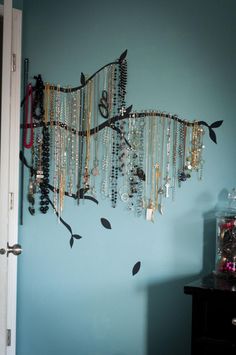 a room with blue walls and jewelry hanging on the wall next to a black dresser