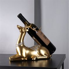 a gold deer figurine with a bottle of wine in it's mouth