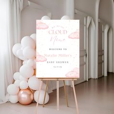 a welcome sign for a baby shower with pink and white balloons on the floor next to it