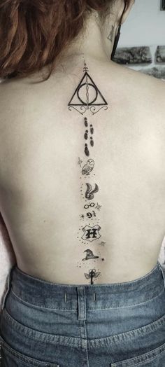 the back of a woman's upper back tattoo with symbols and stars on it