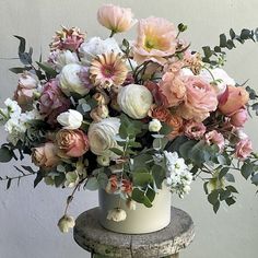 a white vase filled with lots of pink and white flowers