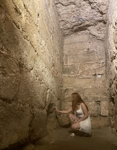 a woman kneeling down in an old stone tunnel