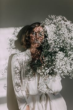 a woman is holding flowers in front of her face