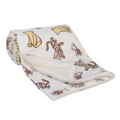 a white blanket with brown and yellow animal designs on it, folded to the side