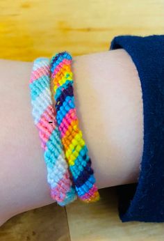 two colorful bracelets sitting on top of a person's arm