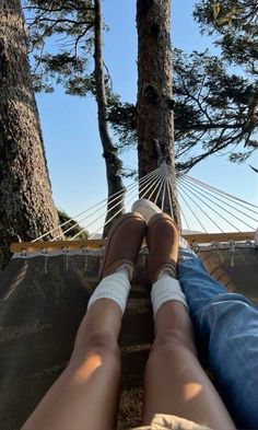 a person sitting in a hammock with their feet propped up on the ground