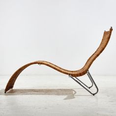 a chair made out of wicker sitting on top of a white floor next to a wall