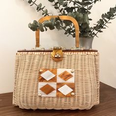 a wicker purse sitting on top of a wooden table next to a potted plant