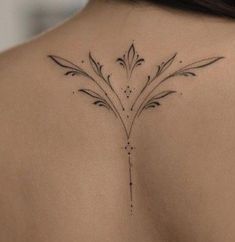 the back of a woman's shoulder with a small flower tattoo on her left side