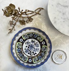 a blue and white plate sitting on top of a table next to a vase with flowers