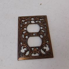 a decorative metal outlet cover on a white surface