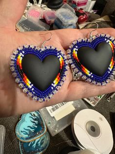 a pair of heart shaped beaded earrings in the palm of someone's hand