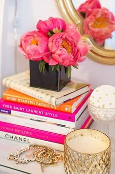 a stack of books sitting on top of a table next to a vase filled with flowers