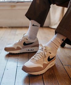 a person wearing white socks and brown shoes sitting on a wooden floor next to a window