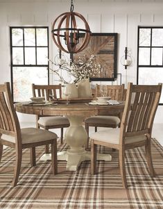 a dining room table with chairs and a rug on the floor in front of it