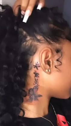 a woman with tattoos on her neck and behind her ear is combing her hair