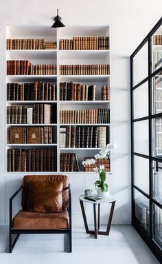 a leather chair sitting in front of a book shelf filled with books