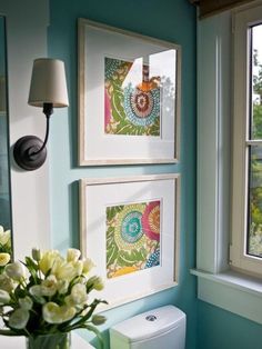 a bathroom with blue walls and pictures hanging on the wall, along with a toilet