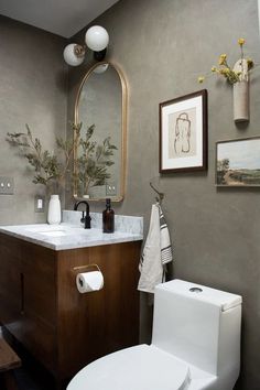 a white toilet sitting next to a wooden cabinet in a bathroom under a large mirror