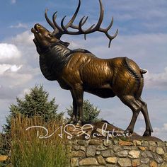 a bronze statue of a deer standing on top of a rock wall